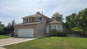 Traditional-style house featuring stucco siding, driveway, brick siding, and a garage