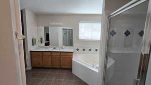 Bathroom featuring vanity, a whirlpool tub, a stall shower, and tile patterned flooring