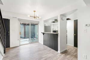 Kitchen with a chandelier, light wood-style floors, freestanding refrigerator, white cabinetry, and light countertops