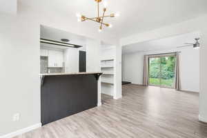 Kitchen with a chandelier, light wood finished floors, white cabinets, and open floor plan