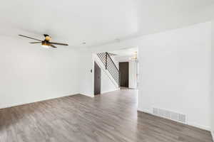 Unfurnished room with stairway, light wood-style floors, ceiling fan, and a chandelier