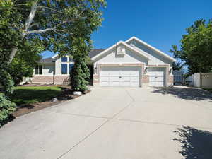 View of front of house with an attached garage, concrete driveway, brick siding, and stucco siding