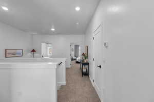 Corridor featuring light colored carpet, recessed lighting, and an upstairs landing