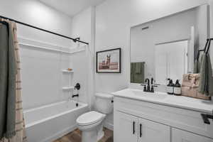 Bathroom with shower / tub combo with curtain, vanity, and wood finished floors