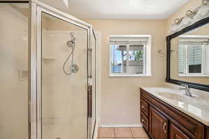 Full bathroom featuring tile patterned floors, a stall shower, and vanity