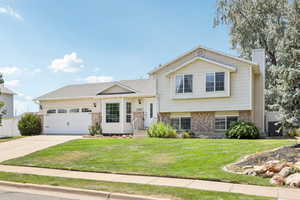 Tri-level home with brick siding, a chimney, driveway, an attached garage, and roof with shingles