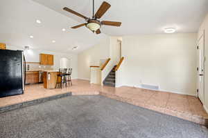 Living room featuring light tile patterned floors, lofted ceiling, recessed lighting, light carpet, and stairs