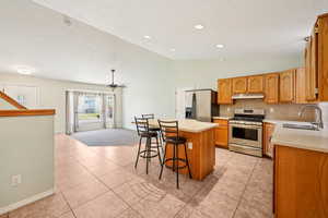 Kitchen with stainless steel appliances, vaulted ceiling, backsplash, light countertops, and a center island