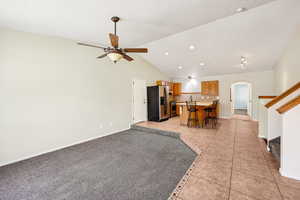 Living area with light tile patterned floors, arched walkways, high vaulted ceiling, stairway, and recessed lighting