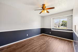 Spare room featuring wood finished floors, ceiling fan, and a textured ceiling