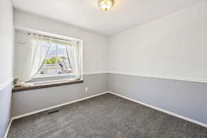 Empty room with carpet and a textured ceiling
