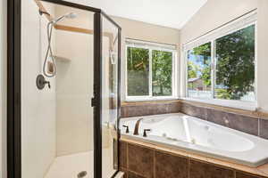 Bathroom featuring a stall shower, a whirlpool tub, and lofted ceiling