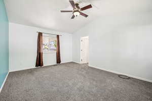 Carpeted empty room featuring lofted ceiling and ceiling fan