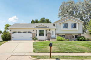 View of front of home with brick siding, a front yard, a garage, concrete driveway, and a shingled roof