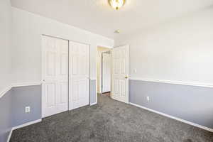 Unfurnished bedroom featuring carpet floors, a textured ceiling, and a closet
