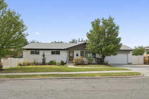 View of front of home with driveway, an attached garage, brick siding, a chimney, and roof with shingles