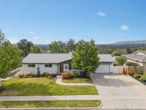 Ranch-style home featuring driveway, roof with shingles, an attached garage, and a chimney