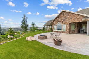View of grassy yard featuring a patio, a fire pit, and a mountain view