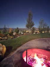 Yard at twilight featuring a lawn and an outdoor fire pit