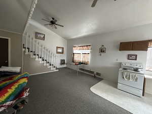 Kitchen with electric range, vaulted ceiling, a ceiling fan, carpet flooring, and a baseboard heating unit
