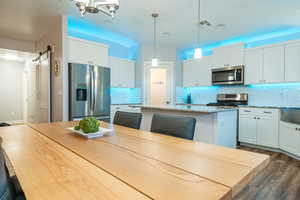 Kitchen featuring appliances with stainless steel finishes, tasteful backsplash, a barn door, a kitchen island, and dark wood finished floors