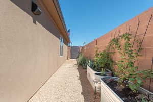 View of property exterior featuring a fenced backyard, stucco siding, and a garden