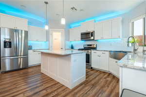 Kitchen featuring stainless steel appliances, decorative backsplash, white cabinets, and a kitchen island