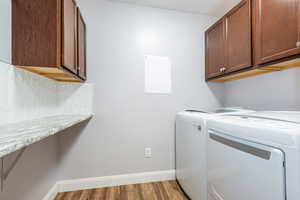 Laundry room featuring independent washer and dryer, wood finished floors, and cabinet space
