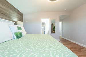 Bedroom with wood finished floors, vaulted ceiling, and wooden walls