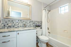 Full bathroom featuring shower / tub combo, vanity, backsplash, and wood finished floors