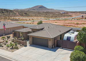 View of front of property featuring a gate, an attached garage, stucco siding, stone siding, and concrete driveway