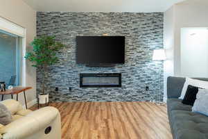 Living area featuring wood finished floors and a glass covered fireplace