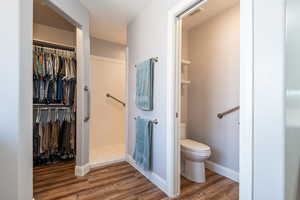 Full bath featuring wood finished floors, a walk in closet, and a walk in shower
