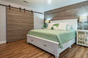 Bedroom with a barn door, wood finished floors, and wood walls