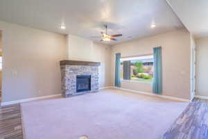 Unfurnished living room with wood finished floors, a fireplace, ceiling fan, and recessed lighting