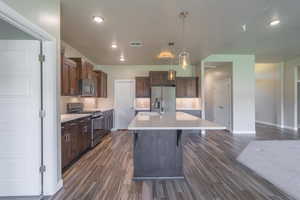 Kitchen featuring backsplash, appliances with stainless steel finishes, light countertops, dark wood-style flooring, and recessed lighting