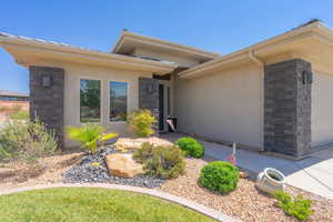 View of exterior entry featuring stone siding, stucco siding, and an attached garage