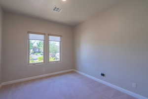Empty room with light colored carpet and recessed lighting