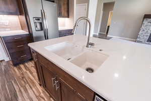 Kitchen featuring stainless steel refrigerator with ice dispenser, light countertops, decorative backsplash, and wood finished floors