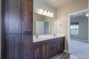 Full bathroom featuring double vanity, wood finished floors, and a ceiling fan