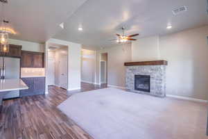 Unfurnished living room featuring a fireplace, ceiling fan, and dark wood-type flooring