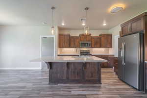 Kitchen featuring backsplash, stainless steel appliances, light countertops, a kitchen island with sink, and recessed lighting