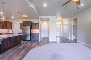 Kitchen featuring dark wood finished floors, stainless steel fridge, a ceiling fan, light countertops, and backsplash