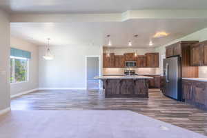 Kitchen featuring backsplash, light countertops, stainless steel appliances, a kitchen bar, and dark wood-style floors