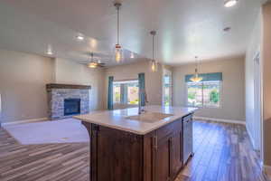 Kitchen with a fireplace, ceiling fan, light countertops, wood finished floors, and recessed lighting