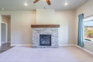 Unfurnished living room with carpet, recessed lighting, a stone fireplace, and ceiling fan