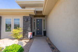 Doorway to property featuring stone siding and stucco siding