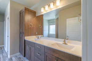 Bathroom with double vanity and wood finished floors
