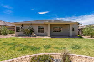 Rear view of property with a lawn, stucco siding, a tiled roof, and a patio area