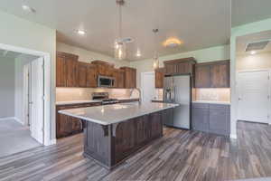 Kitchen with stainless steel appliances, decorative backsplash, light countertops, an island with sink, and recessed lighting